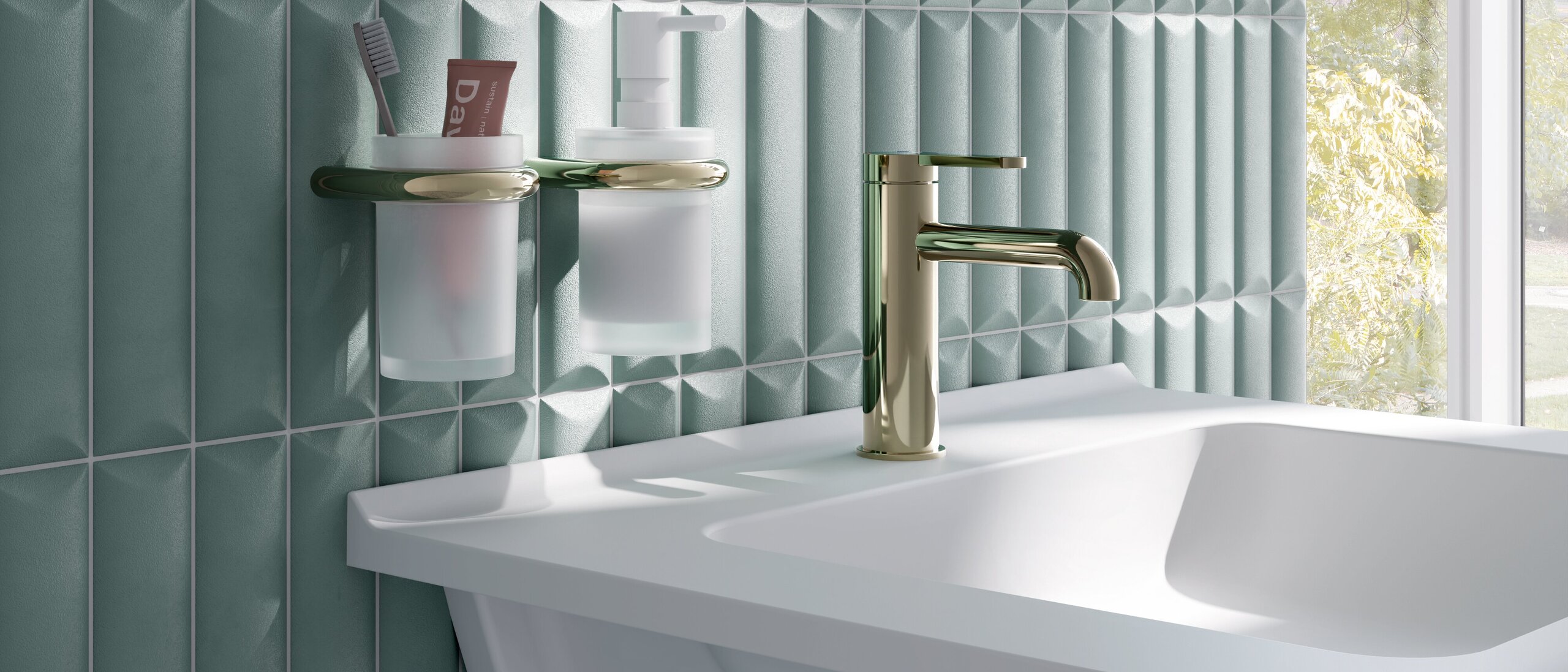Wandhalterungen mit Becher und Seifenspender neben Waschbecken, Wasserhahn und Siphon in messingfarbener Optik an blauer Fliesenwand