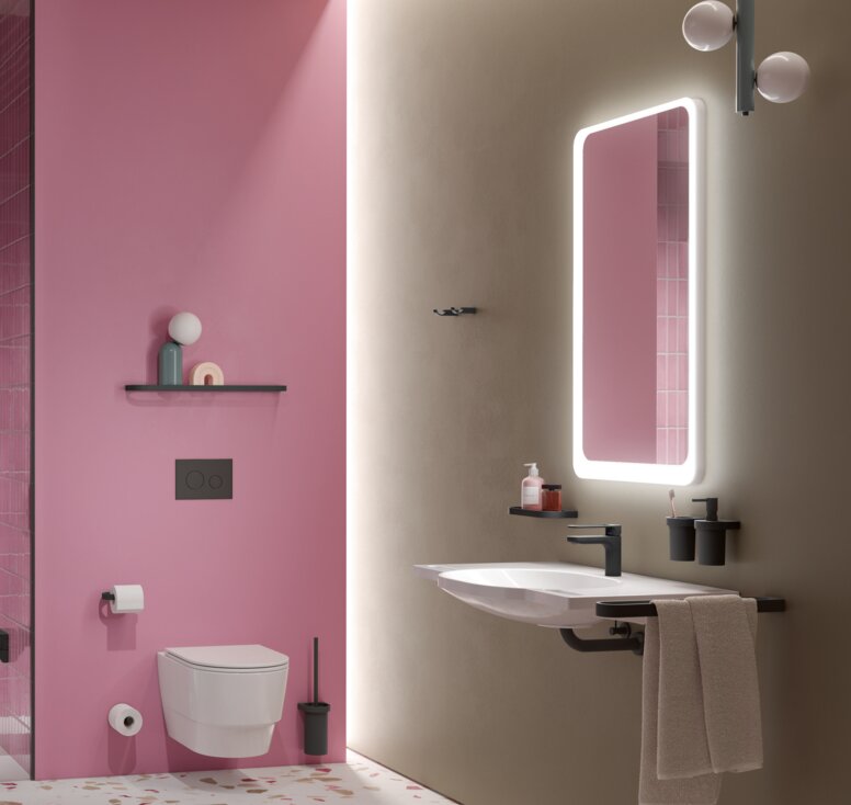 Klappbarer Sitz neben Brausehandlauf in einer Dusche mit Hocker und rosa Fliesen, daneben WC und Waschtisch mit Spiegel