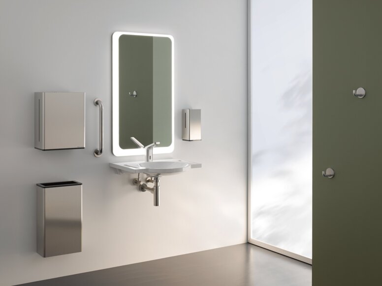 HEWI Range 805 Interior A lighted mirror, with a washbasin underneath, complete with a paper towel dispenser and a waste bin, against a white wall
