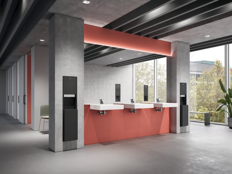 Three washbasins in the public area, set against grey-and-red concrete walls, with paper and soap dispensers recessed into the wall