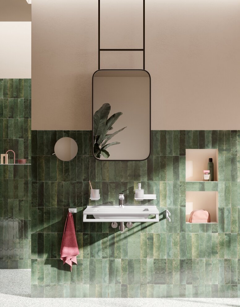 Barrierefreies Waschbecken mit Wasserhahn sowie wandhängendes WC und barrierefreier Duschbereich mit Klappsitz an grüner Fliesenwand