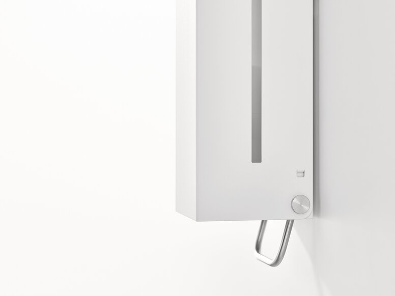 HEWI System 900 soap dispenser White wall-mounted soap dispenser with a viewing window and an operating lever on the underside against a white background