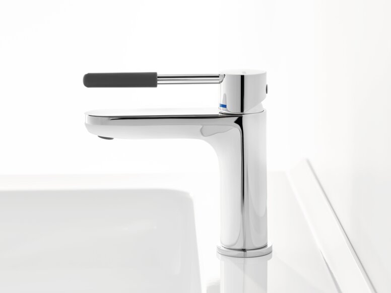 HEWI AQ single-lever washbasin mixer tap Chrome-plated tap with a long lever handle and dark grey grip sleeve on a white washbasin against a white background